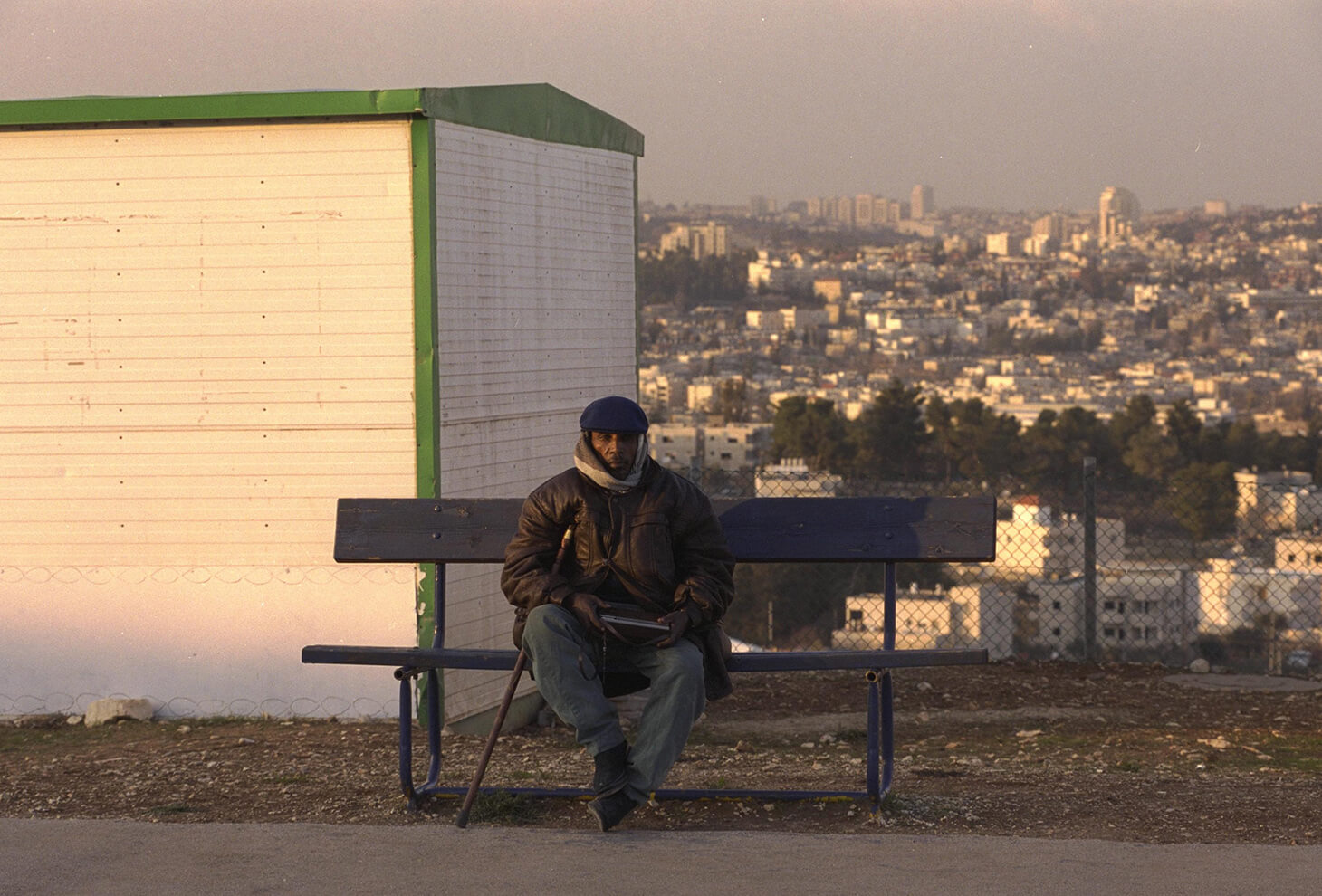 AN ETHIOPIAN IMMIGRANT LISTENING TO A RADIO ON A BENCH AT 